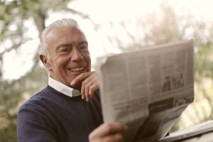 smívající se dobře vypadající důchodce čte noviny