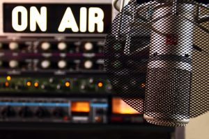 detail na mikrofon v nahrávacím studiu v pozadí s nahrávací technikou a panelem